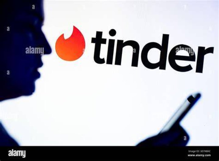 a Tinder logo seen displayed on a smartphone on top of a computer keyboard.