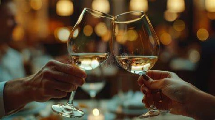 People clinking glasses in wine taste as they celebrate a birthday party in backyard People clinking glasses in wine taste as they celebrate a birthday party in backyard